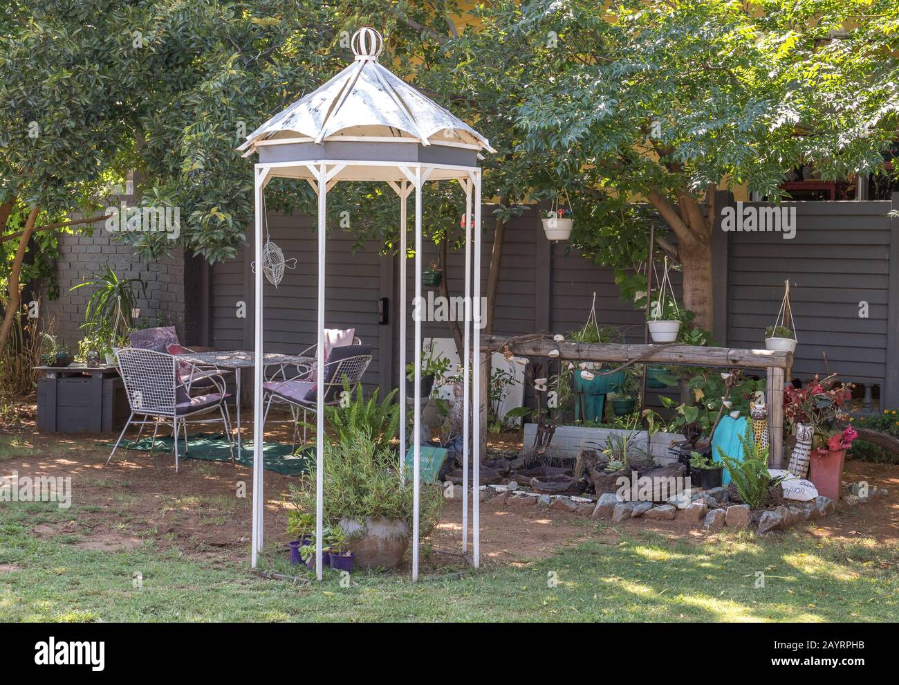Ein ruhiger, schattiger Ort in einem Garten unter Bäumen mit Bank- und Sesselbild im horizontalen Format Stockfoto