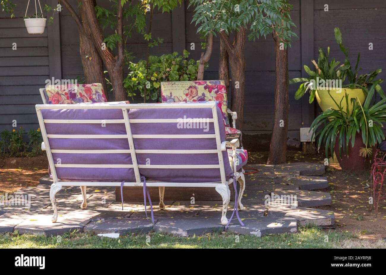 Ein ruhiger, schattiger Ort in einem Garten unter Bäumen mit Bank- und Sesselbild im horizontalen Format Stockfoto