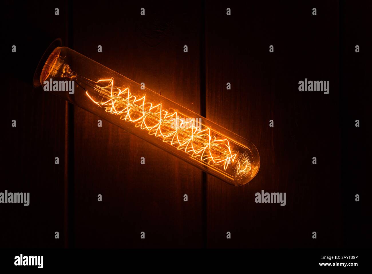 Eine Pendelleuchte mit brennender Glühlampe für Inneneinrichtung glänzt im Dunkeln. Stockfoto