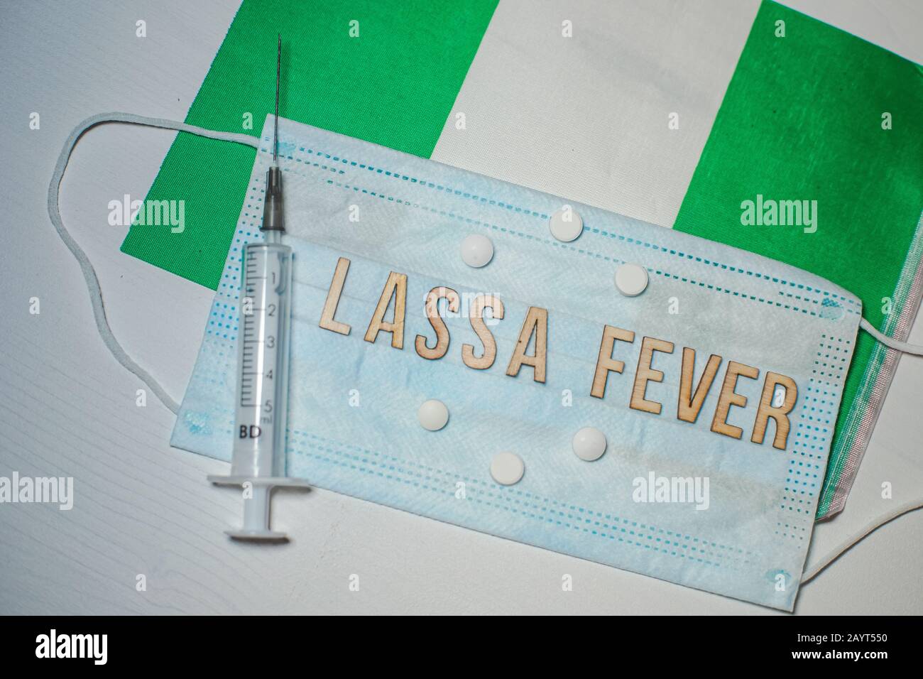 Nigerianische Flagge unter den Worten Lassa Fever Outbreak-Konzept. Atemschutzmaske und Spritze. Lassa hämorrhagisches Fieber LHF endemisch in Westafrika inkl Stockfoto