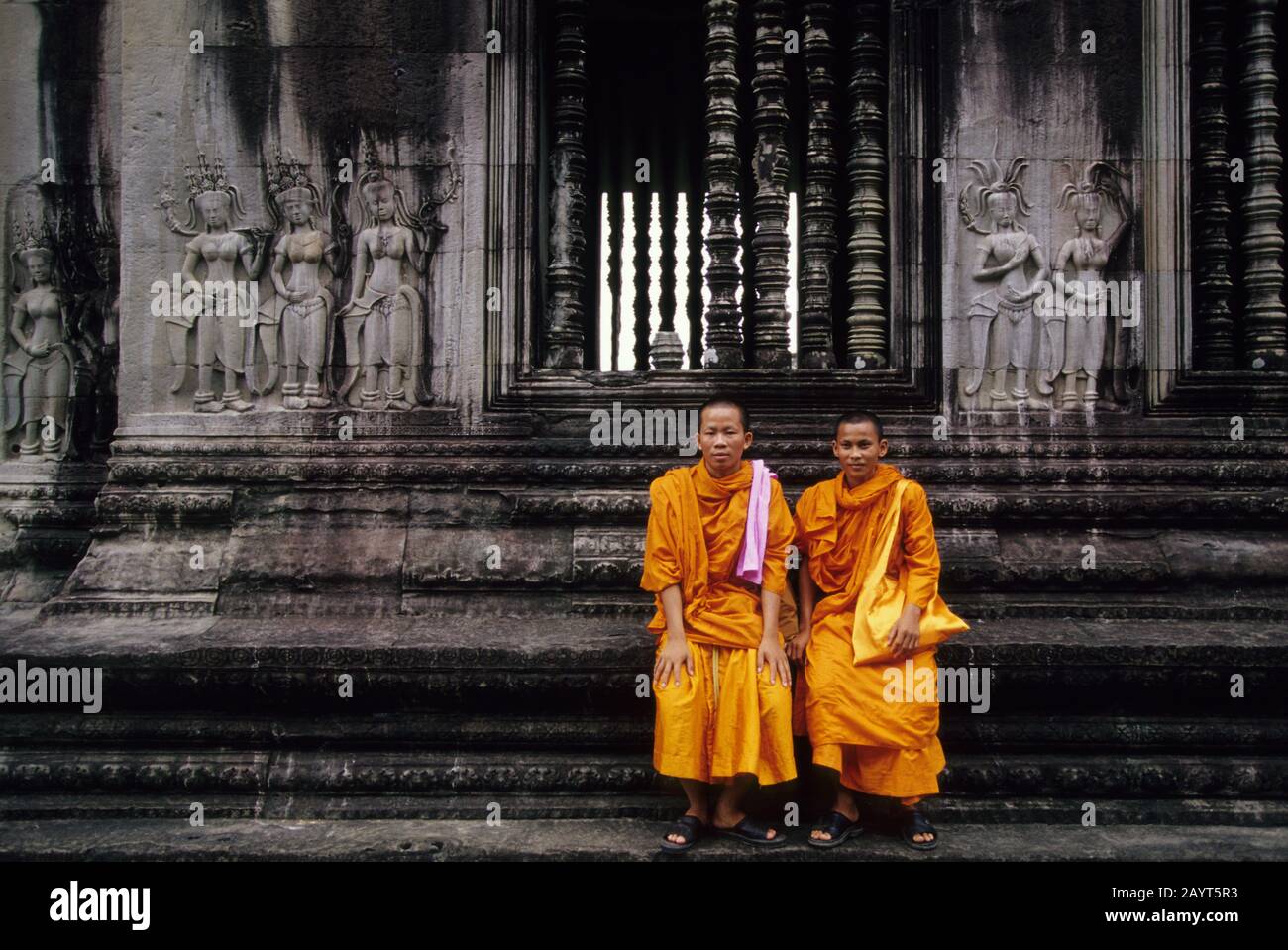 Novizen (Monks), die auf einer der Terrassen des Angkor Wat Tempels in Angkor in Siem Reap in Kambodscha sitzen. Stockfoto