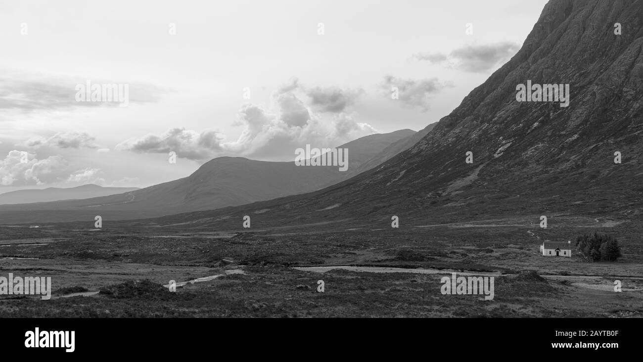Eine schwarz-weiße schottische Landschaft mit einem kleinen weißen Cottage und trübem Himmel Stockfoto