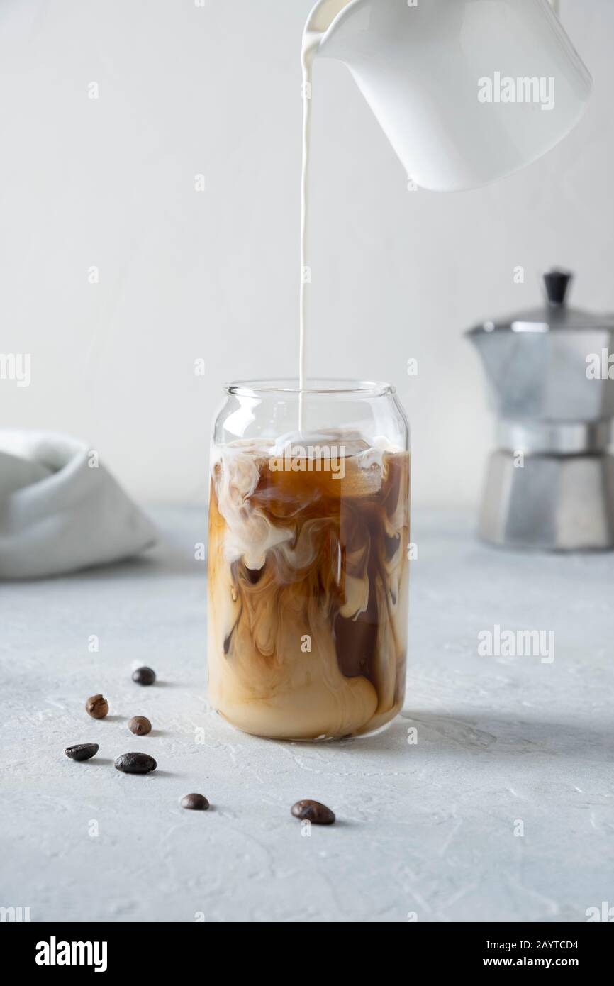 Eiskaffee aus Glas mit Milch auf Grau. Nahaufnahme. Vertikales Format. Stockfoto