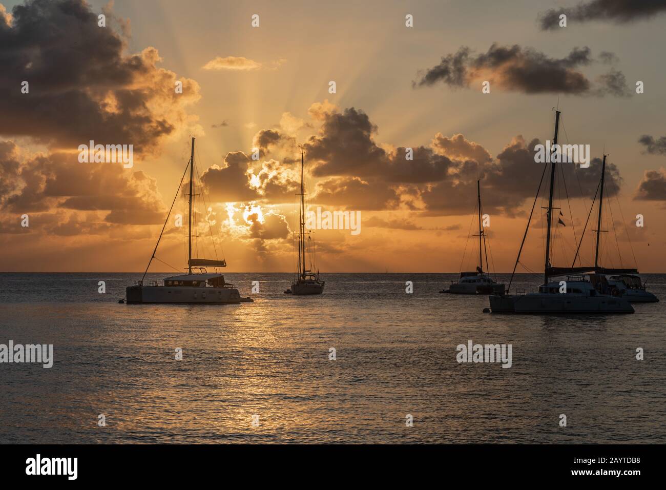 Blick auf den Sonnenuntergang von Yachten und Katamaranen, die in der Lagune, der Bucht von Britannia, der Insel Mustique, Saint Vincent und die Grenadinen, dem karibischen Meer, verankert sind Stockfoto