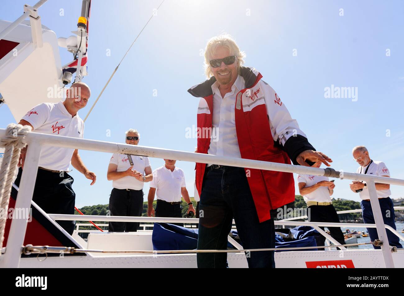 Sir Richard Branson mit der ursprünglichen und neuen Crew des Virgin Atlantic Challenger II, die im Hafen von Fowey ankam, um ihre Wiedervereinigung zu feiern. Stockfoto