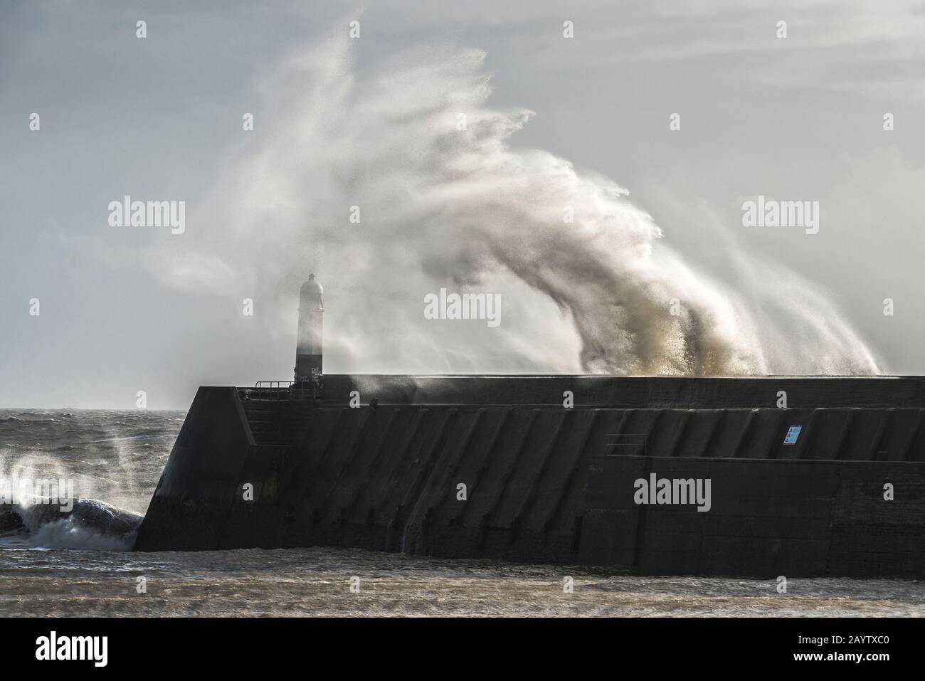 Sturm Dennis bringt hohe Winde und sendet Wellen, die über den Leuchtturm bei Porthcawl in Südwales brechen (16. Februar 2020) Stockfoto