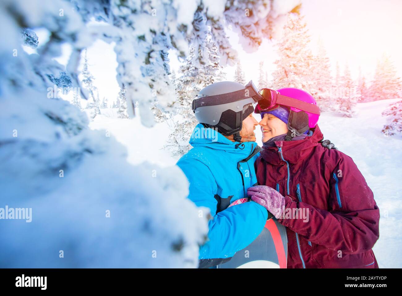 Liebevolles Paar in Anzügen umarmen und küssen sich im Hintergrund des Winterwaldes. Familienurlaub Stockfoto