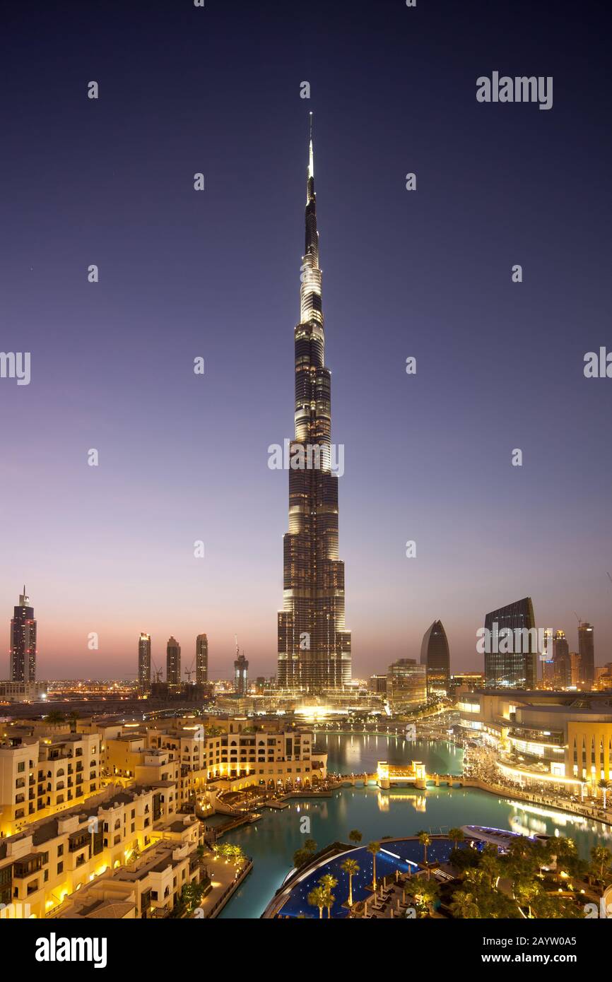 Der Burj Khalifa und die Innenstadt Dubais werden bei Sonnenuntergang beleuchtet, während Touristen auf die Spekatulr-Show des Dubai-Brunnens warten. Stockfoto