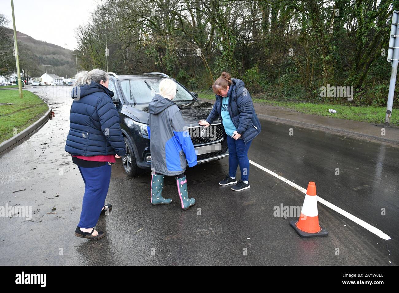 NUMMERNSCHILD PIXELIERT VON PA PICTURE DESK Rachel Cox (ganz rechts) steht neben ihrem neu gekauften Auto, das durch Flutwasser beschädigt wurde, nachdem sie es ein Viertel Meile von ihrem Haus in Nantgarw in Südwales gefunden hat, Wo die Bewohner in ihre Häuser zurückkehren, um die Schäden nach dem Sturm Dennis zu untersuchen und zu beheben. Stockfoto