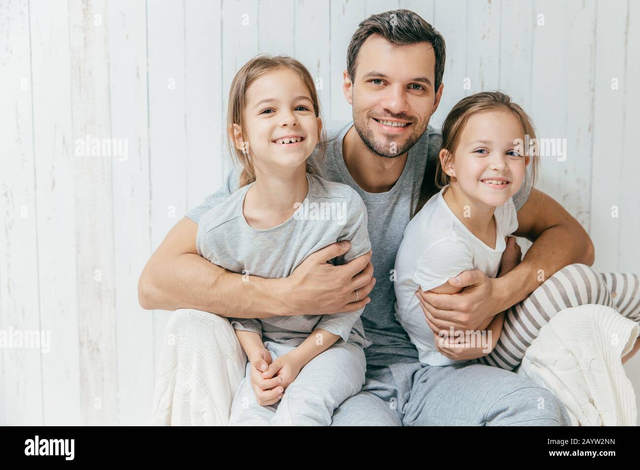Porträt der glückliche junge Vater schließt seine zwei Töchter, liebt sie sehr, gemeinsam zu Hause dar. Einzelnen Vati mit schönen femle Kinder haben Stockfoto