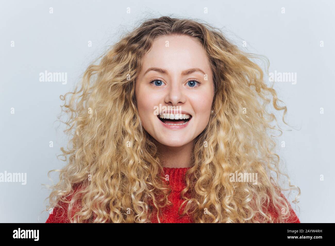 Horizontales Porträt einer fröhlichen, entzückenden Frau mit ansprechendem Look, fühlt sich aufgeregt, als hört man lustige interessante Geschichte, isoliert über weißem Hintergrund. Stockfoto