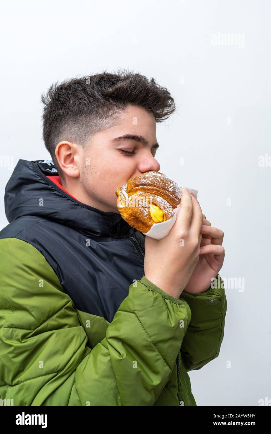 Gluttoniger Teenager, der cremefarbenes Dessert isst und genießt Stockfoto