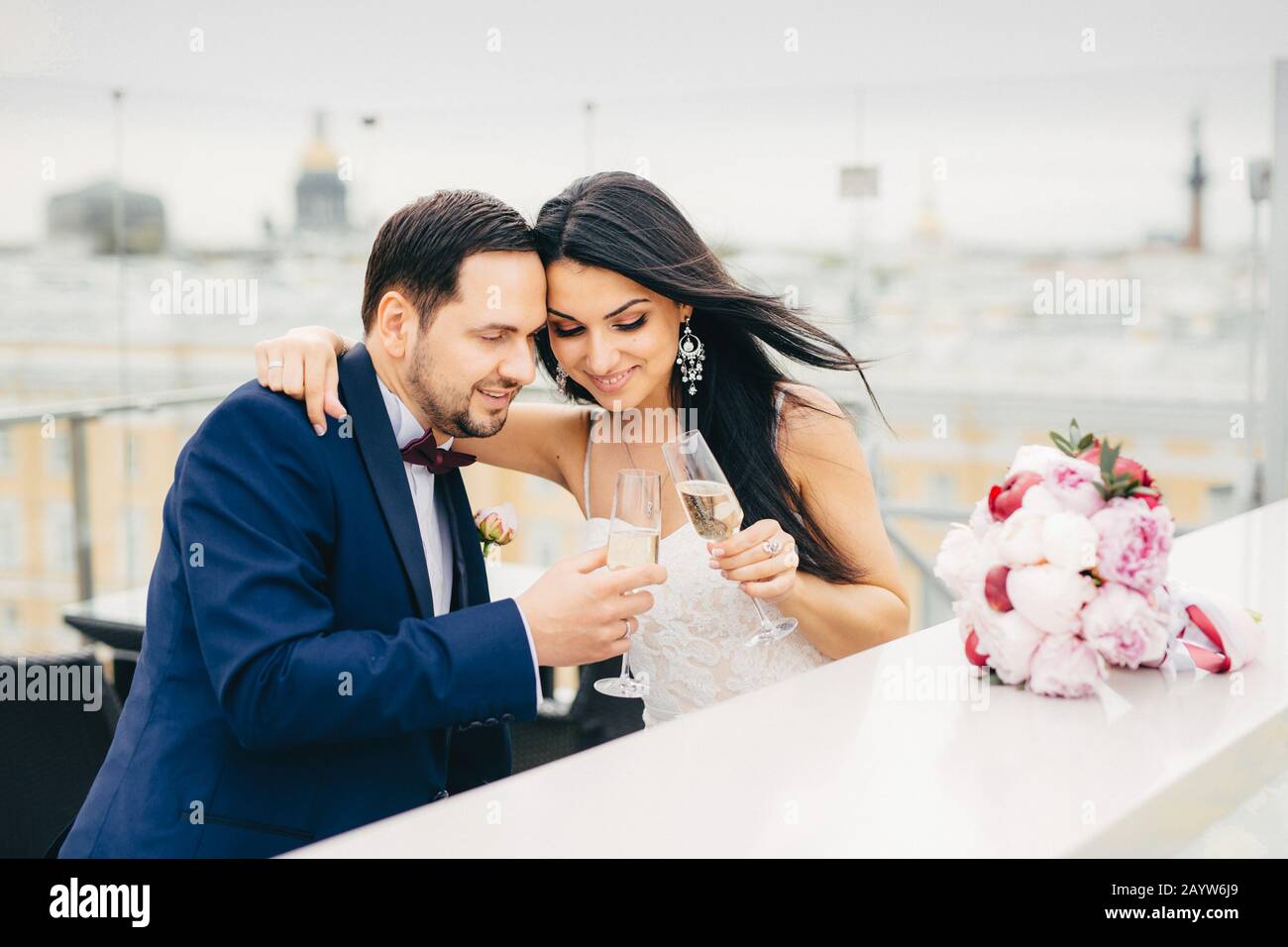 Junges liebevolles Paar mit Champagner in einer Liebesspille, umarmen sich, um ihre Hochzeit zu feiern, und sind froh, eine Familie zu werden, genießen Sie Stockfoto