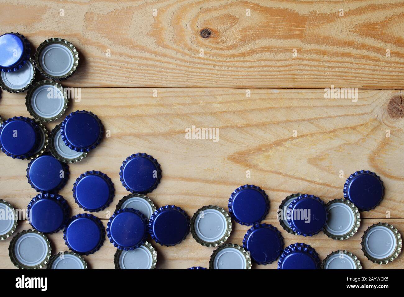 Flacher Laienblick auf blaue Bierflaschenoberteile auf einem rustikalen Holztisch. Home Bierbraukonzept mit Kopierraum . Stockfoto