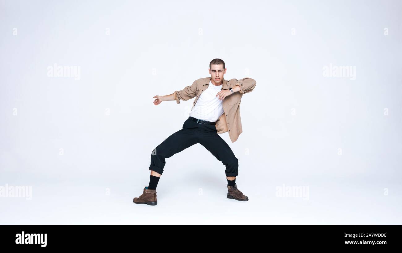 Junger kaukasischer Mann in Tanzpose. Mann in legerer Kleidung, der vor weißem Hintergrund tanzt. Stockfoto