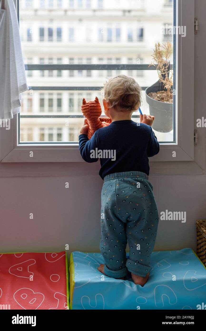 Kaukasisches Kleinkind und sein fuchsförmiges Stofftier starrten ein Fenster aus. Stockfoto