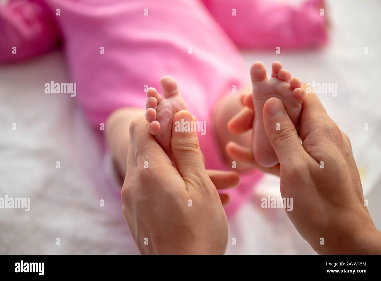 Mutter oder Arzt massieren den Fuß des kleinen Babys Stockfoto