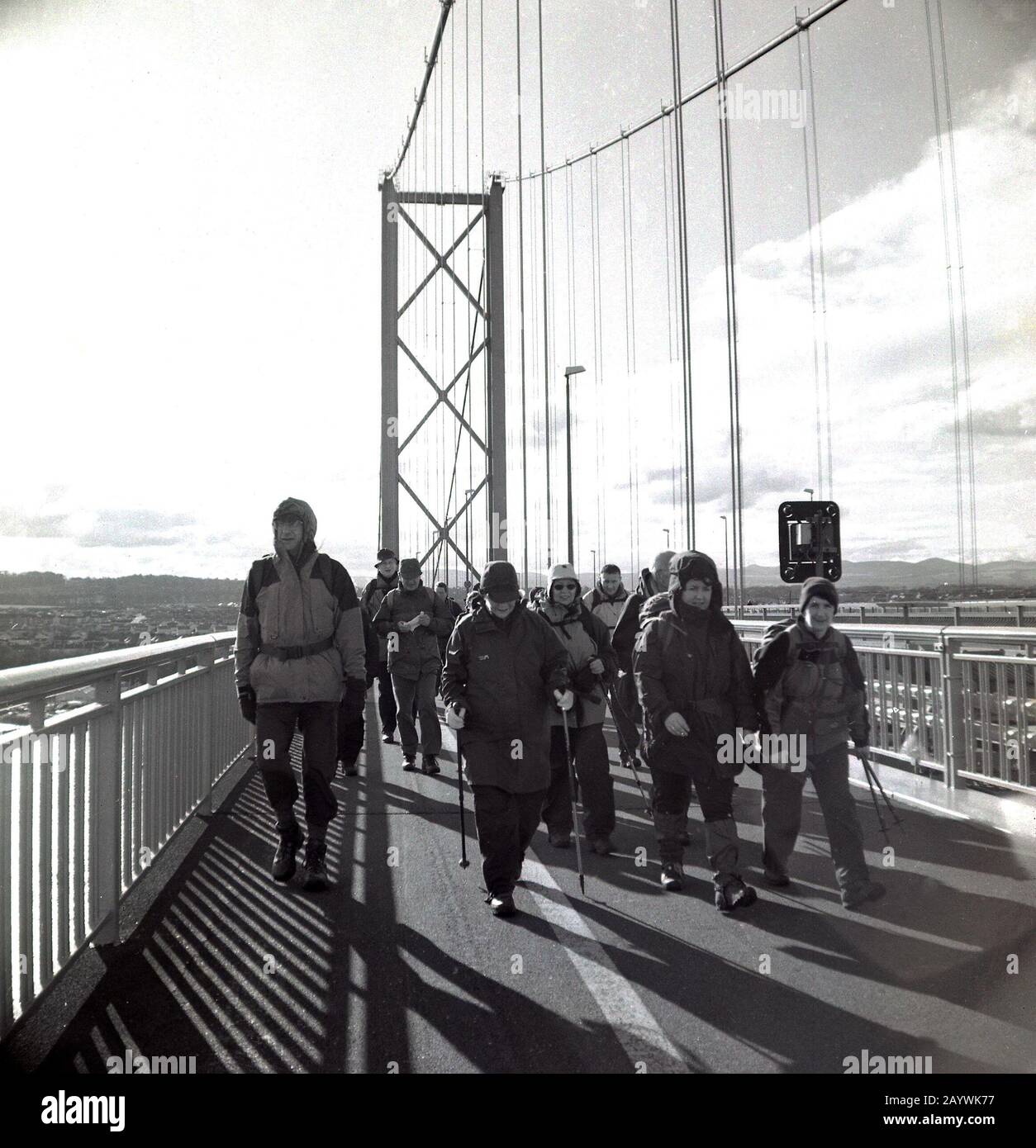 1980er Jahre, eine Gruppe von erwachsenen Wanderern in Wanderausrüstung, die auf der Forth Road Bridge, Stirling, Schottland, entlang geht. Stockfoto