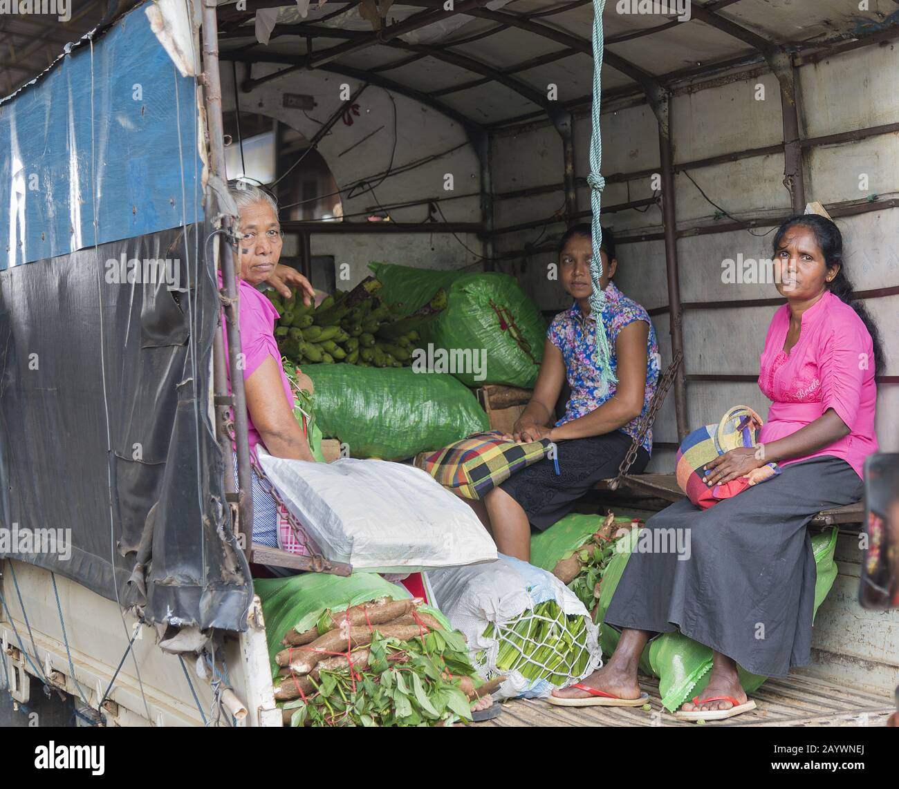 Dambulla, Sri Lanka: 18.03.2019: Frauen auf dem Gemüsemarkt im Großhandel sitzen im Heck eines LKW mit Säcken pflanzlicher Produkte. Stockfoto