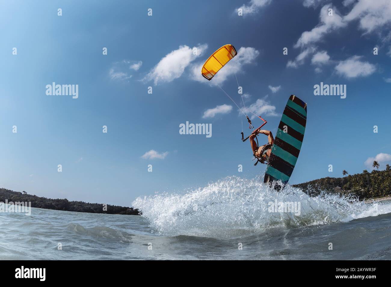 Kitesurfer mit Wakeboard springt gegen blauen Himmel. Wasser-Extremsport-Konzept Stockfoto