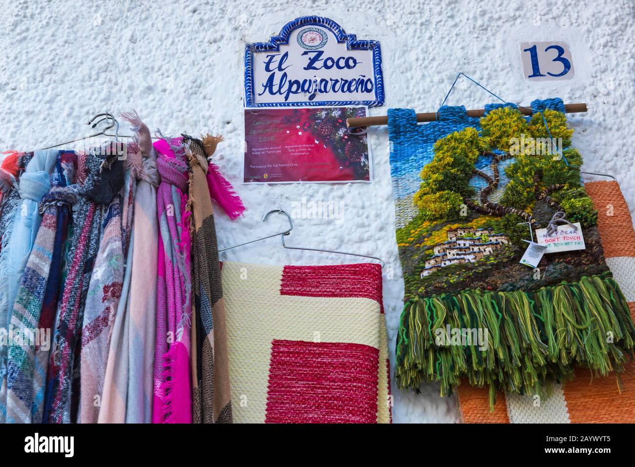 Örtlich herzufügendes Kunsthandwerk, das im Februar vor dem Laden in El Zoco Alpujarreno in Pampaneira, Andalucia, Spanien, hängt Stockfoto
