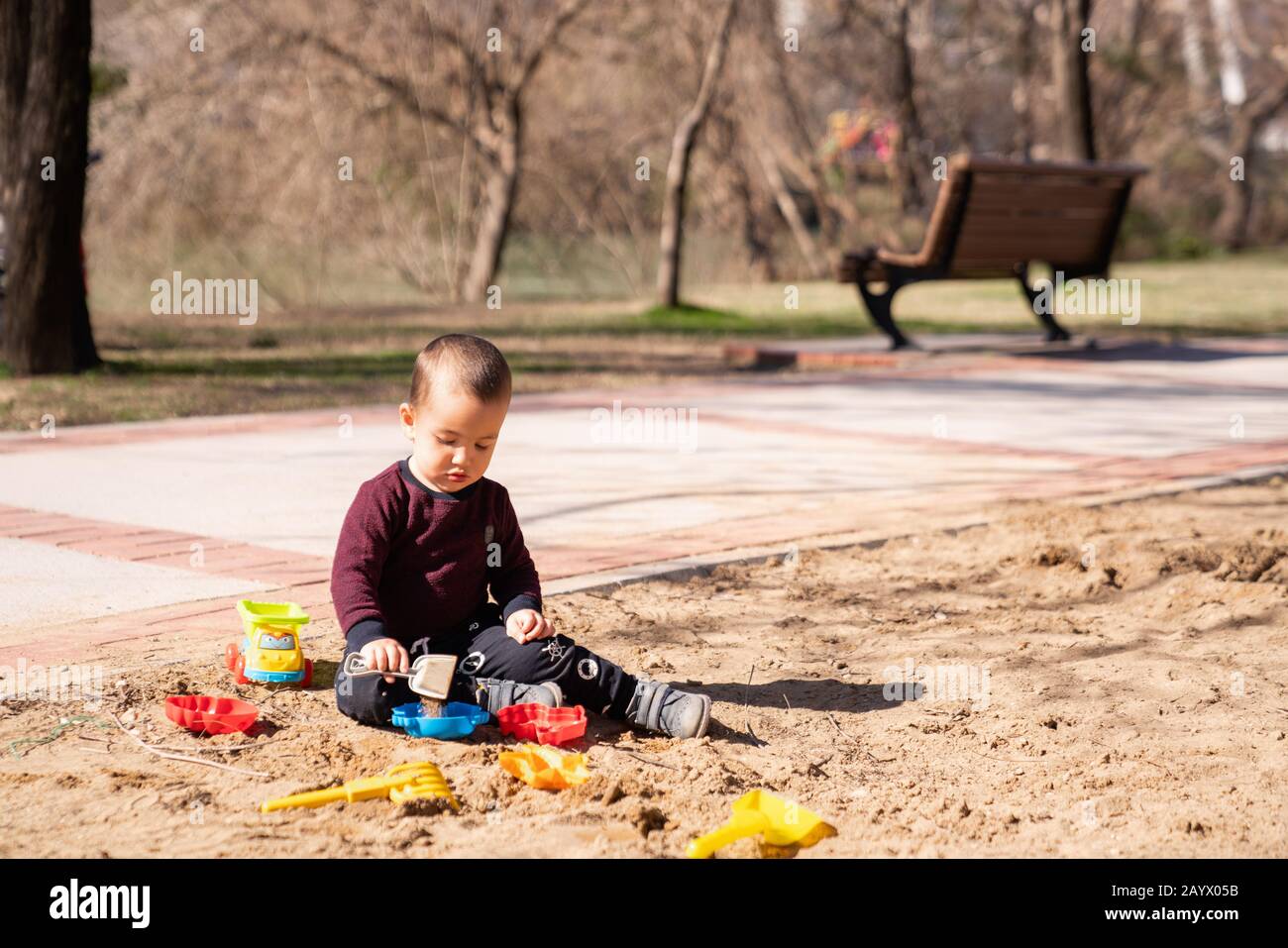 Kleiner süßer Junge, der in Sandbox mit Plastikspielzeug spielt. Konzeptspiel im Freien im Frühjahr oder Sommer Stockfoto