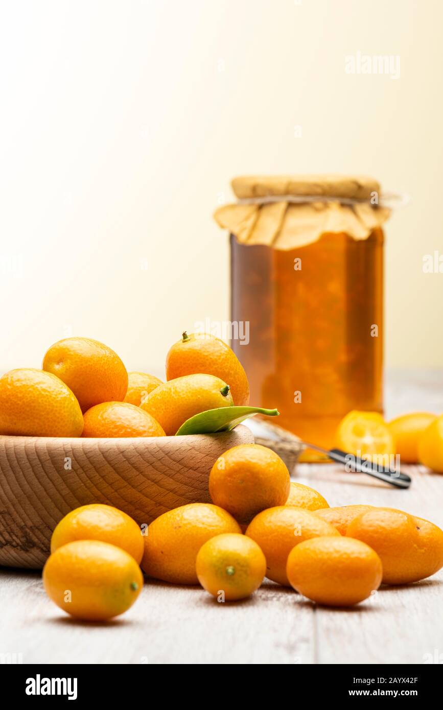 Haufen von kumquat Früchten, chinesische Mandarinen, auf Holztisch mit Marmeladenbecher. Stockfoto