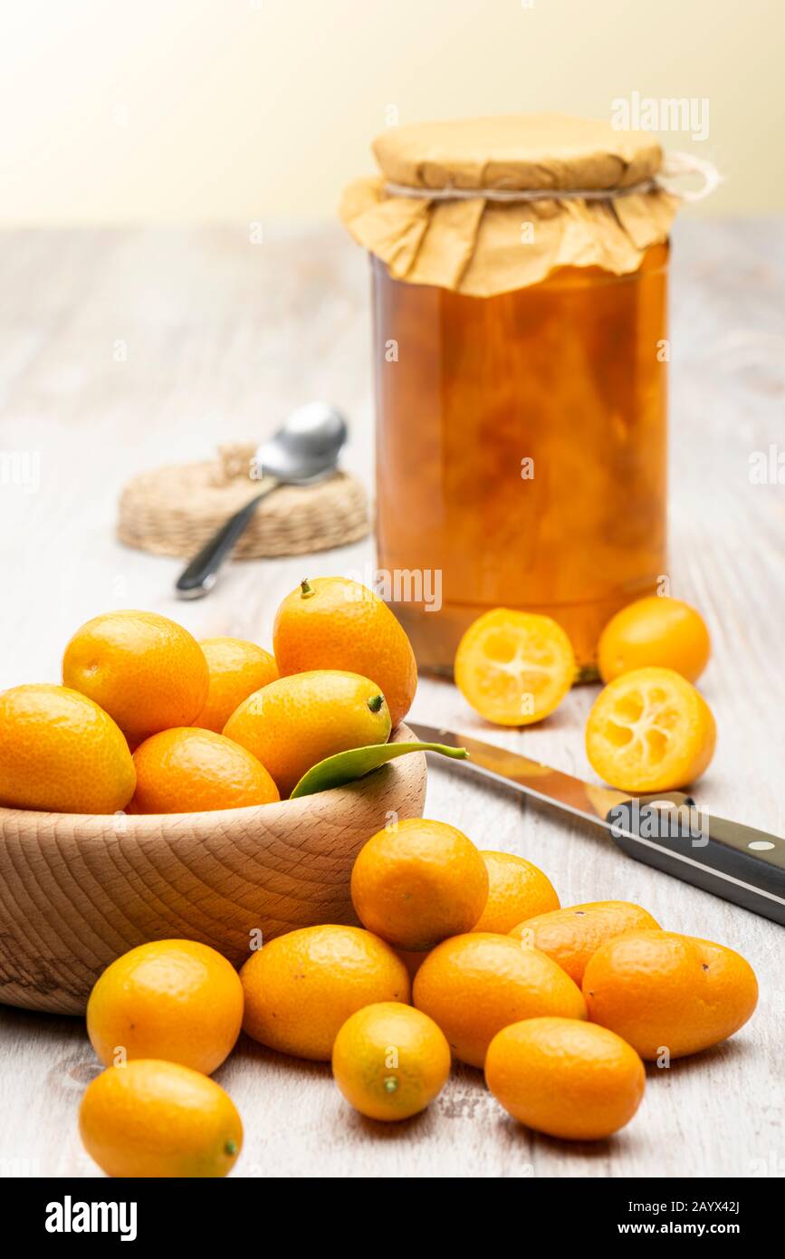 Haufen von kumquat Früchten, chinesische Mandarinen, auf Holztisch mit Marmeladenbecher. Stockfoto