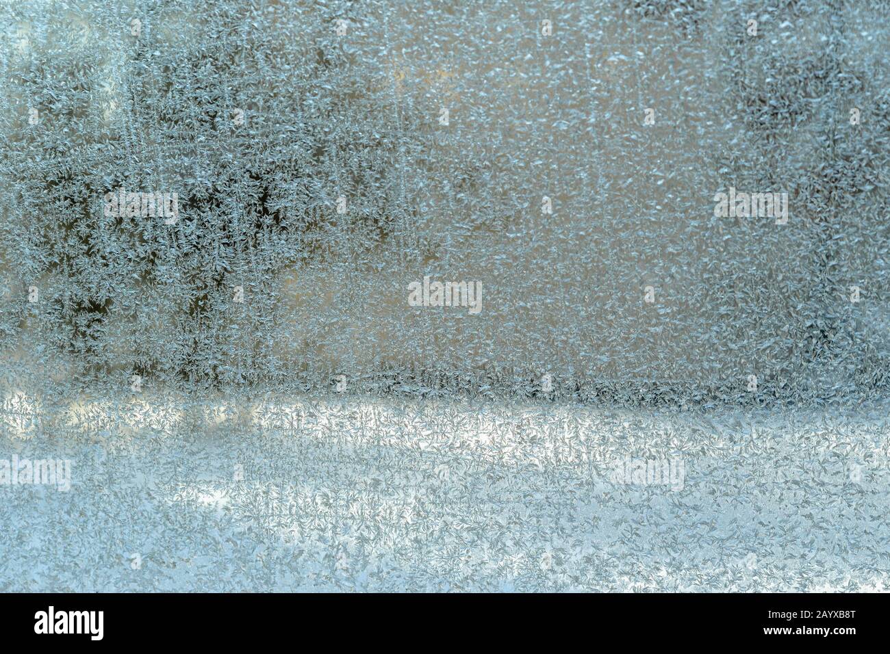 Verschwommene Landschaft hinter dem Fenster und mattes Fensterglas mit beeindruckendem Naturmuster an einem sonnigen Wintertag. Nahaufnahme, abstrakter Hintergrund Stockfoto