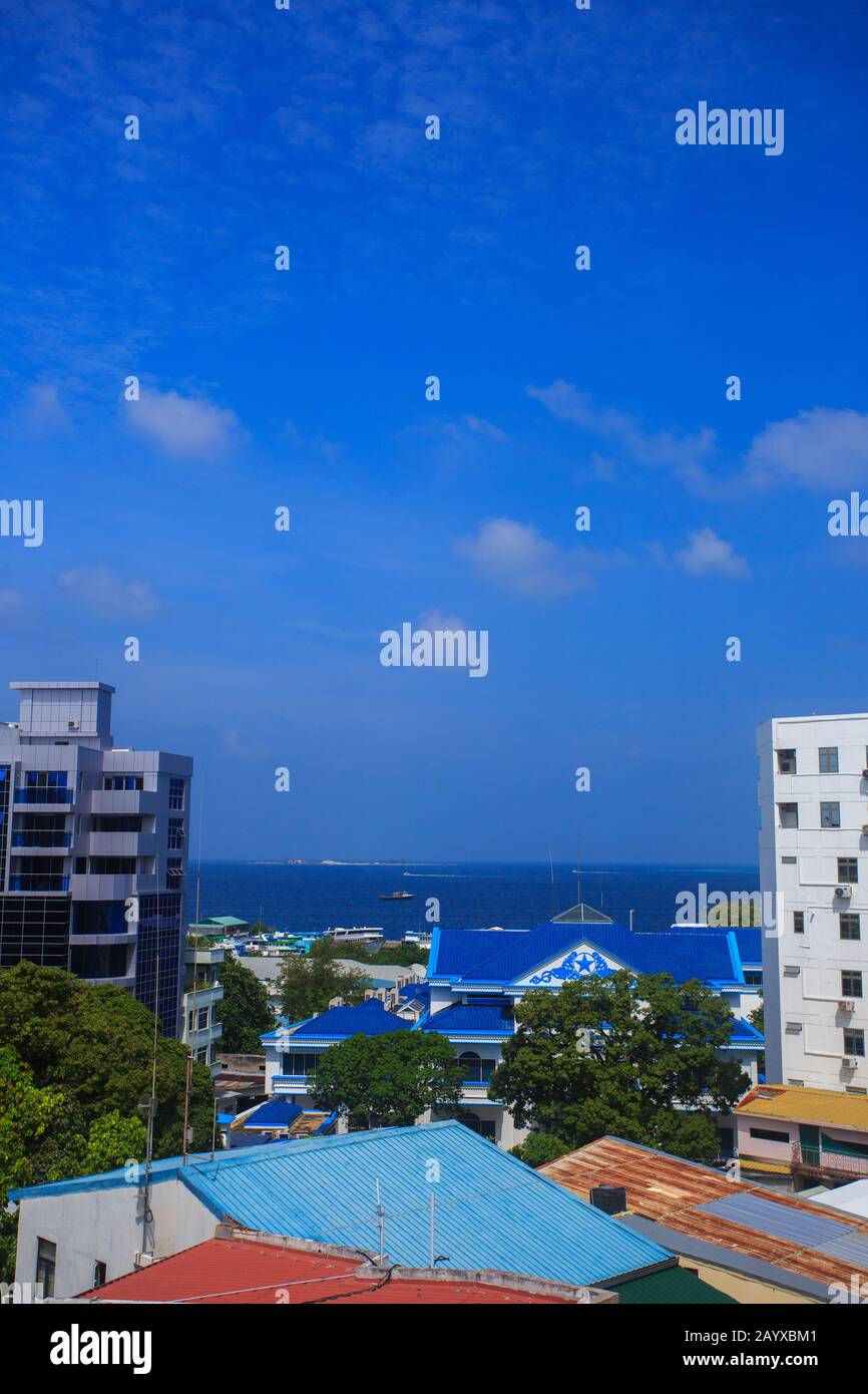 Mehrstöckige Gebäude von Male City (Malediven). Blaues Wasser des Indischen Ozeans ist in einer Entfernung sichtbar. Stockfoto