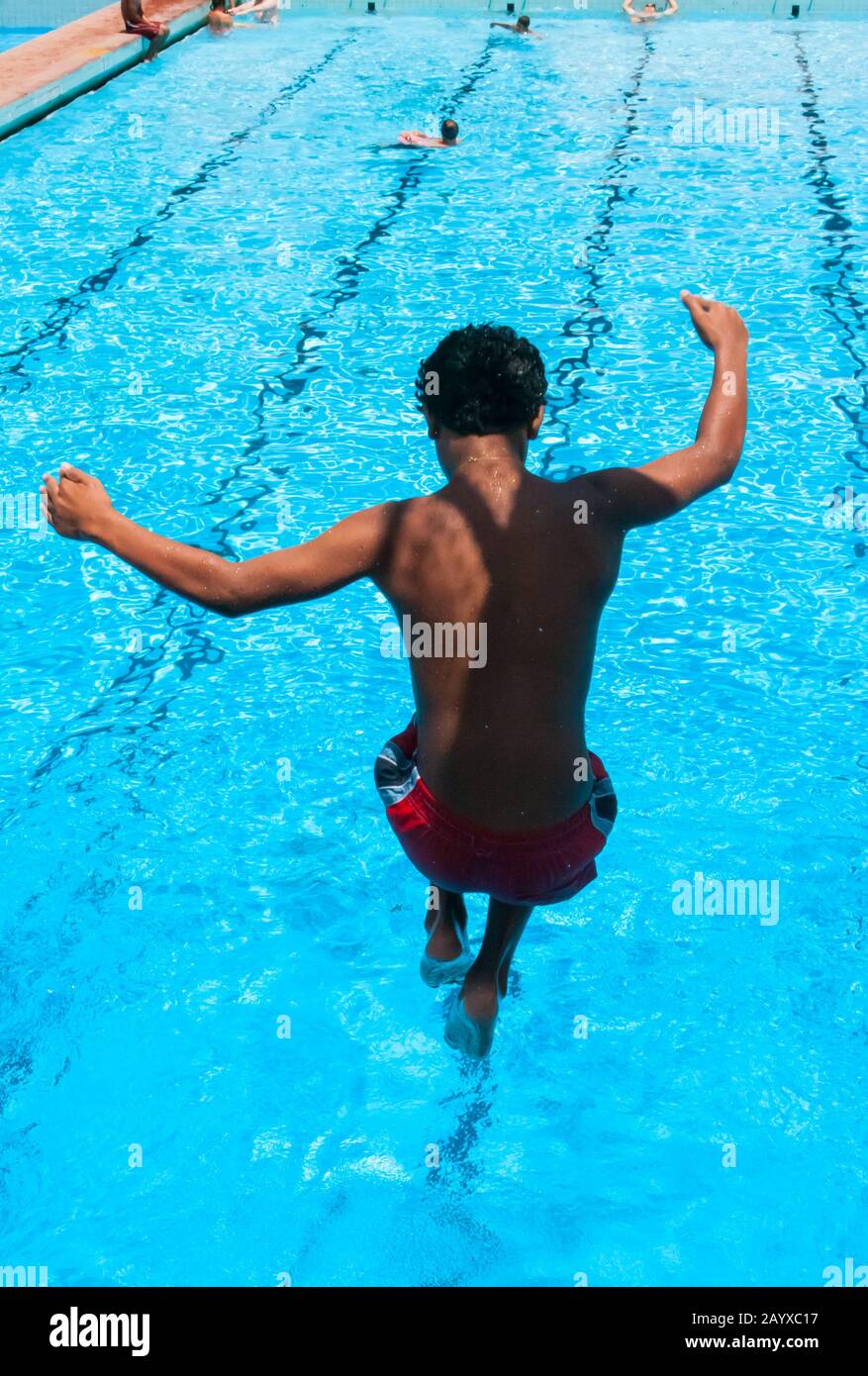 Der Junge taucht in der Luft in den Swimmingpool ein Stockfoto