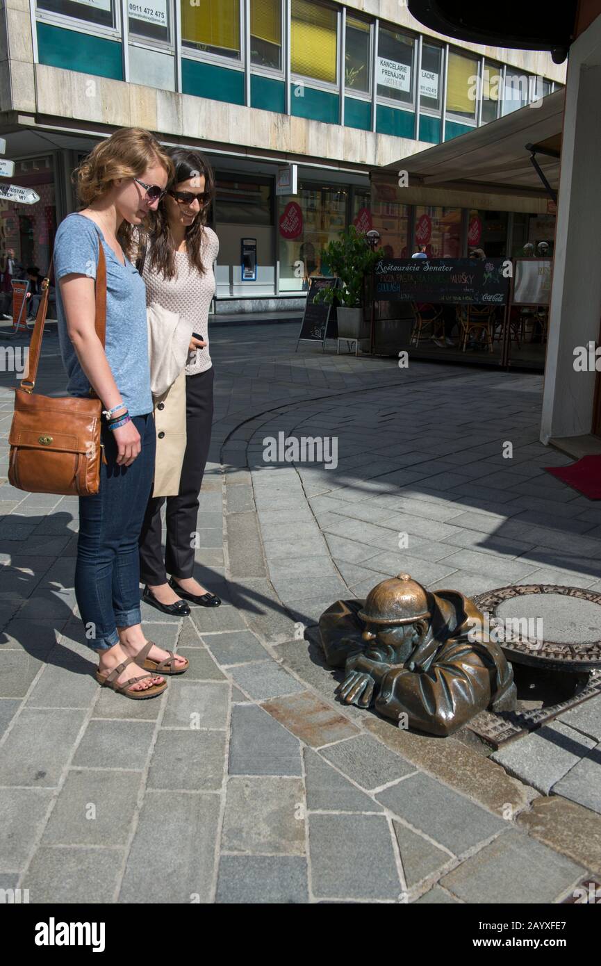 Straßenszene mit Frauen, die die Bronzestatue in Bratislava, der Hauptstadt der Slowakei, betrachten. Stockfoto