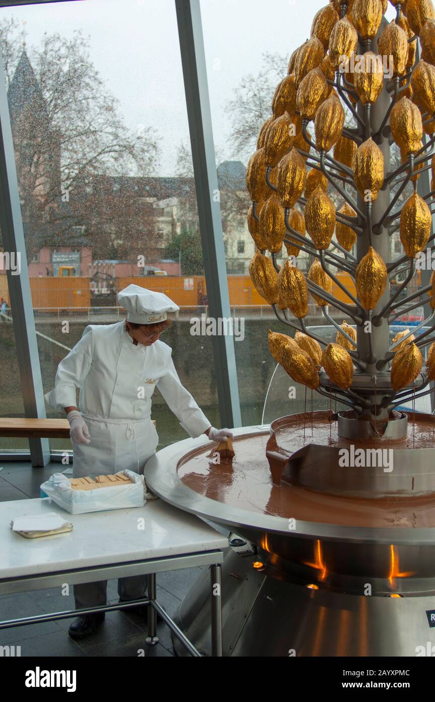Frau taucht im Imhoff-Schokoladenmuseum (Imhoff-Schokoladenmuseum) im Kölner Stadtteil Altstad Waffeln in den Schokoladenbrunnen Stockfoto