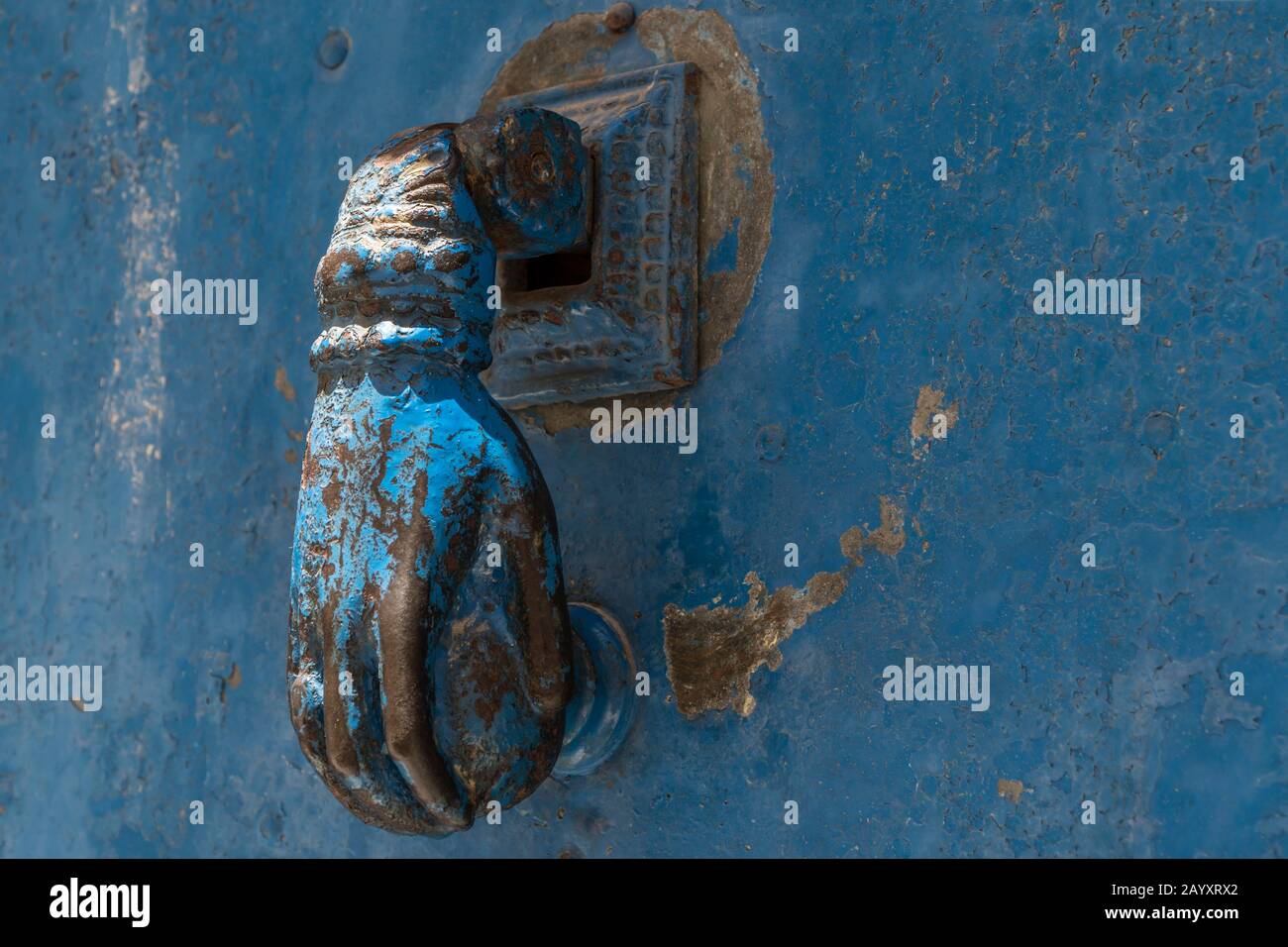 Die handförmige Tür in der Nähe klopft an eine alte und rostige blaue Tür in Anatolien, Türkei Stockfoto