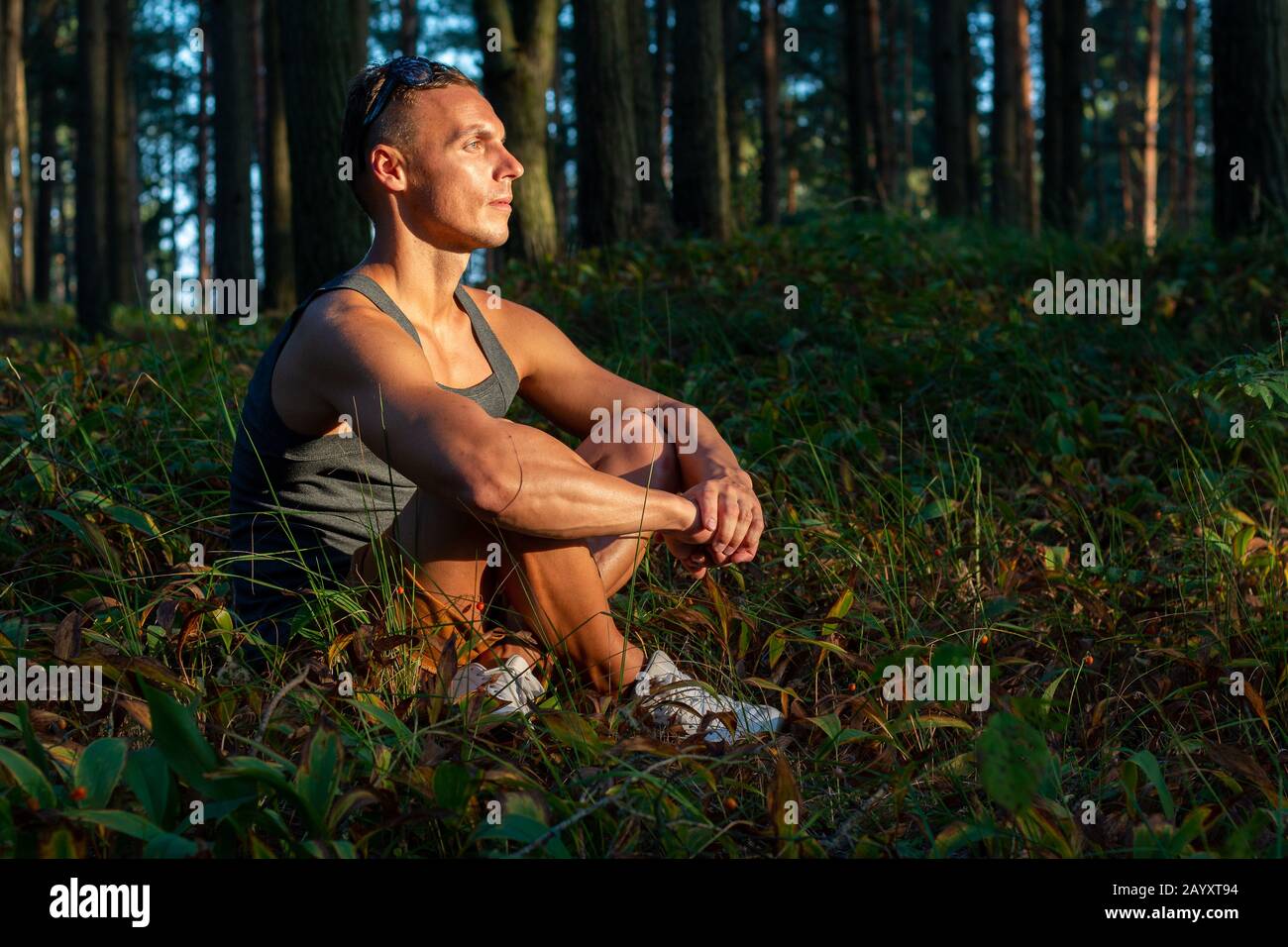 Ein sportlicher Mann im Wald, entspannend bei Sonnenuntergang. Stockfoto