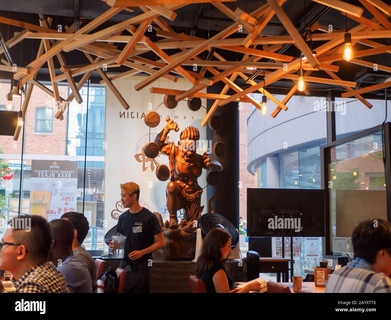 Statue des gottes Raijin schaut auf Menschen, die japanisches Essen in einem Restaurant essen. Stockfoto