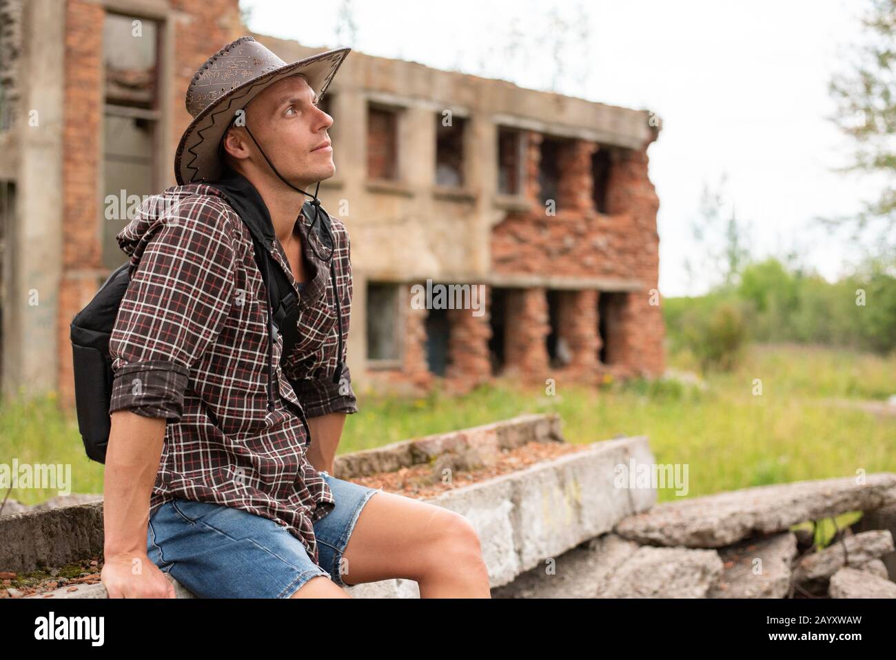 Ein Mann in einem Cowboyhut sitzt inmitten eines zerstörten Hauses. Stockfoto