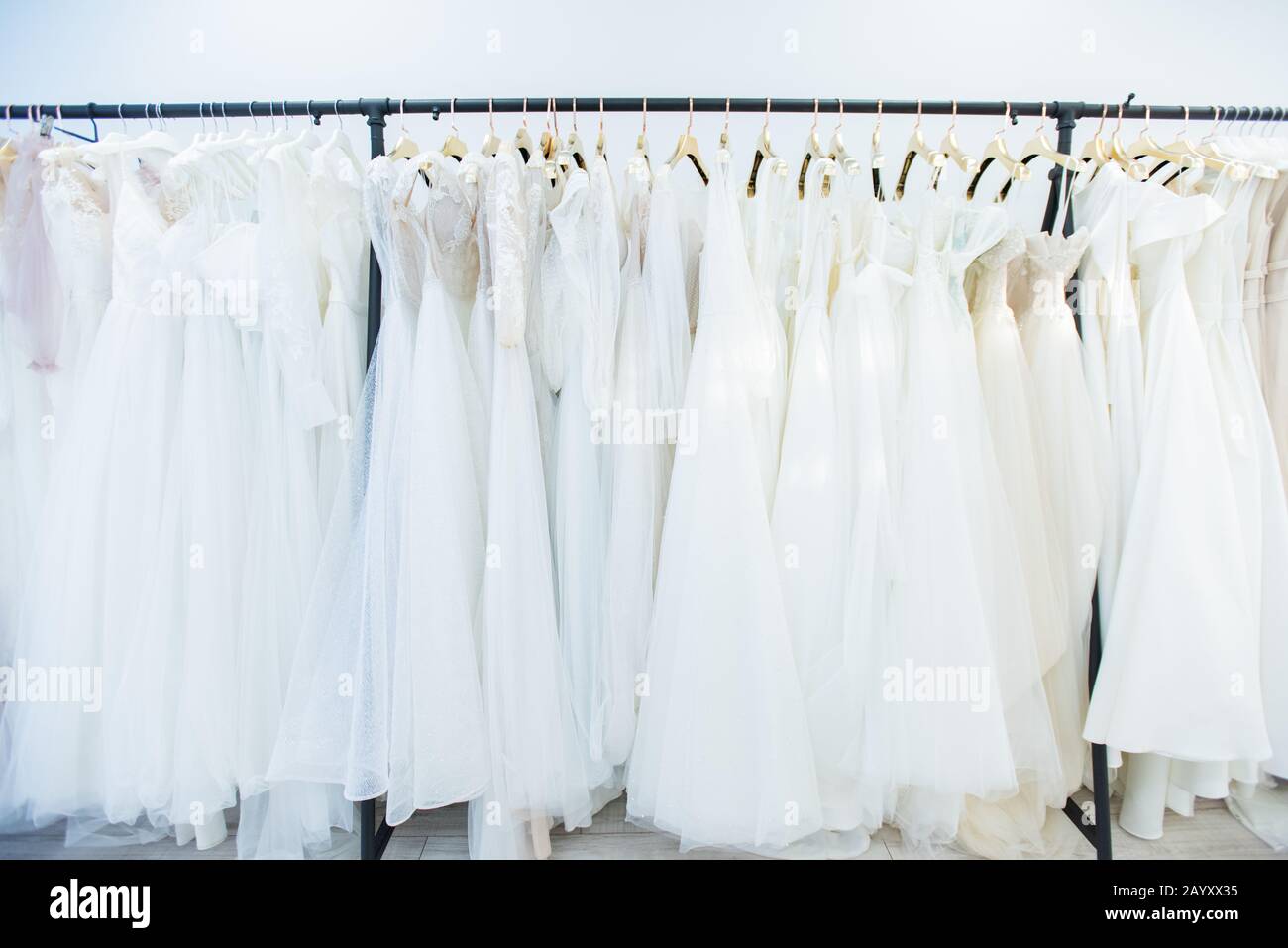 Im modernen brautkleideratelier schossen keine Menschen horizontal auf Kleiderschienen von schönen Hochzeitskleidern Stockfoto