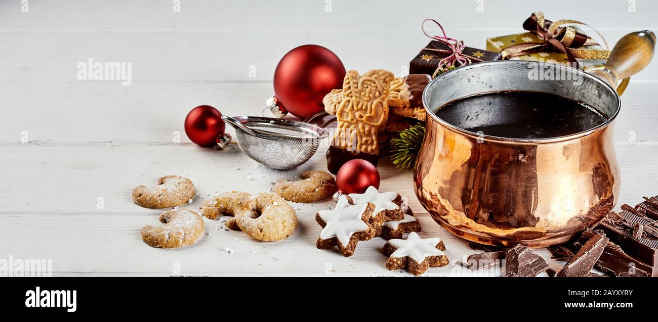 Zubereitung von Schokolade getauchte oder vereiste Weihnachtskekse mit Spekulos, Sternen und halbmondförmigen Keksen neben einem Topf mit geschmolzenem Schokoladendip und Xm Stockfoto