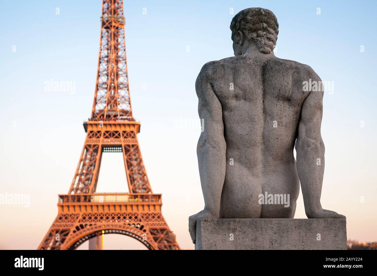 Blick auf den Eiffelturm bei Sonnenuntergang mit einer Nacktstatue eines muskulösen Mannes, L'Homme, des Künstlers Pierre Traverse (1937) im Trocadero in Paris, Frankreich Stockfoto