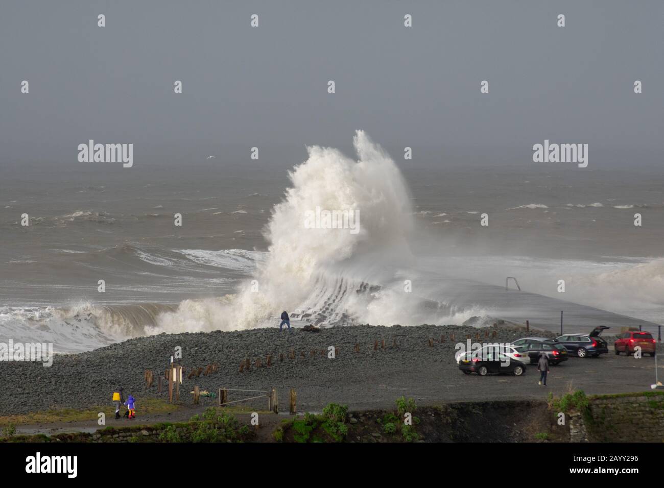 Stürmisches Wetter erzeugt große Wellen, die in Aberystwyth, Wales schwelgen, während Zuschauer von der Größe der Wellen in den Schatten gestellt werden. Stockfoto