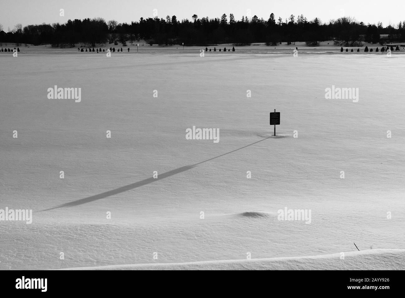 Schwarz-weißer Sonneneinschlag über einen verschneiten, gefrorenen Dow's Lake mit einem Schild "Keep Off the ICE", das einen langen Schatten wirft. Ottawa, Ontario, Kanada. Stockfoto