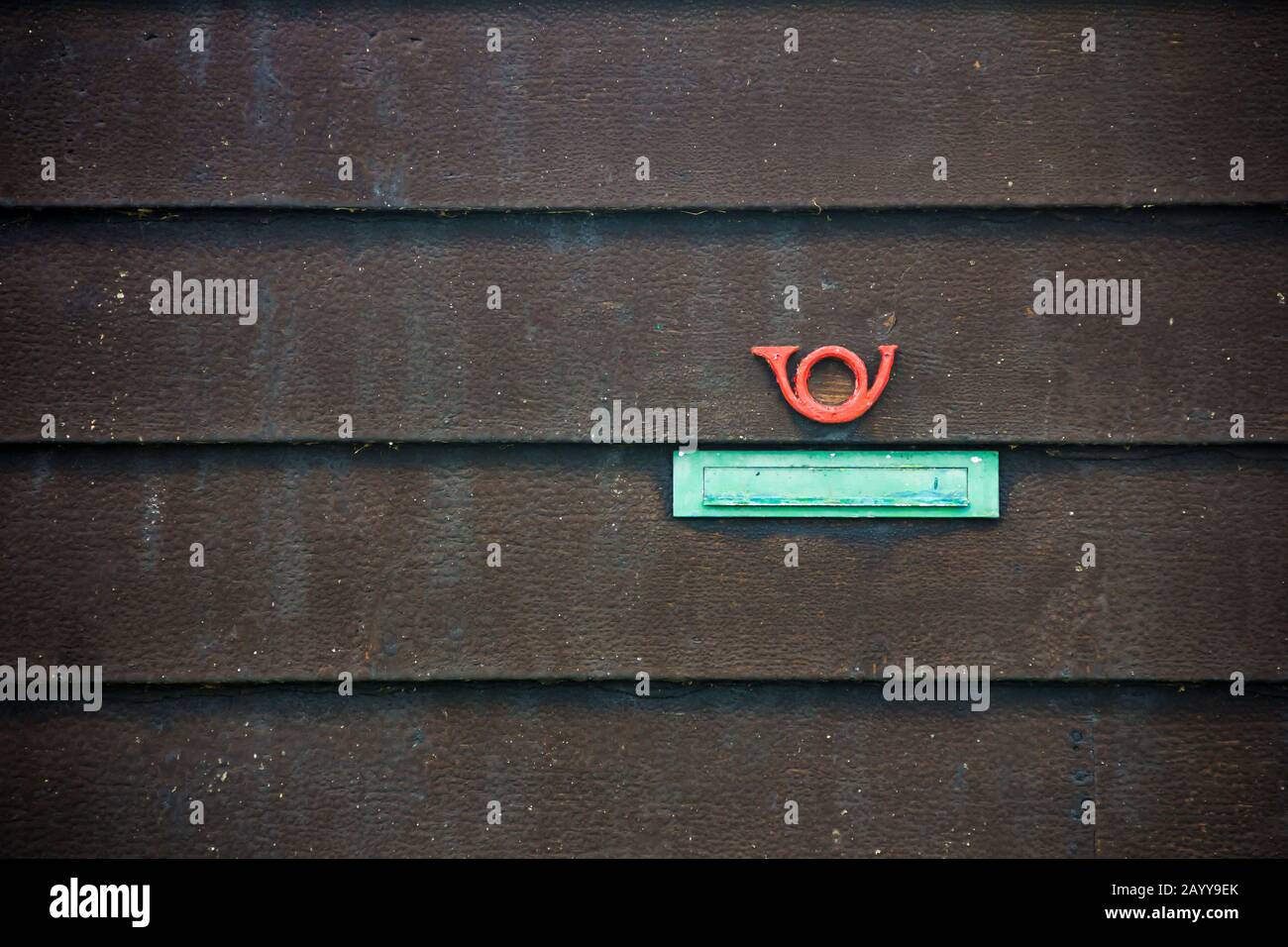 Ein grüner Briefschlitz und ein rotes Schild mit dem Hornpfosten auf schwarzem Holzboardhintergrund Stockfoto