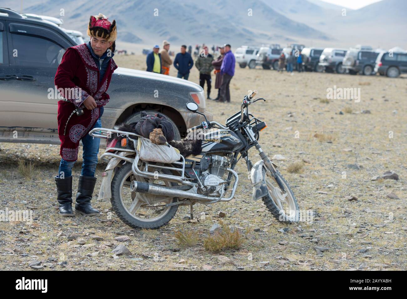 Auf dem Festgelände in der Nähe der Stadt Ulgii (Ölgii) im Bayan-Ulgii Provinc kommen ein kasachischer Adler-Jäger und sein goldener Adler mit dem Motorrad an Stockfoto
