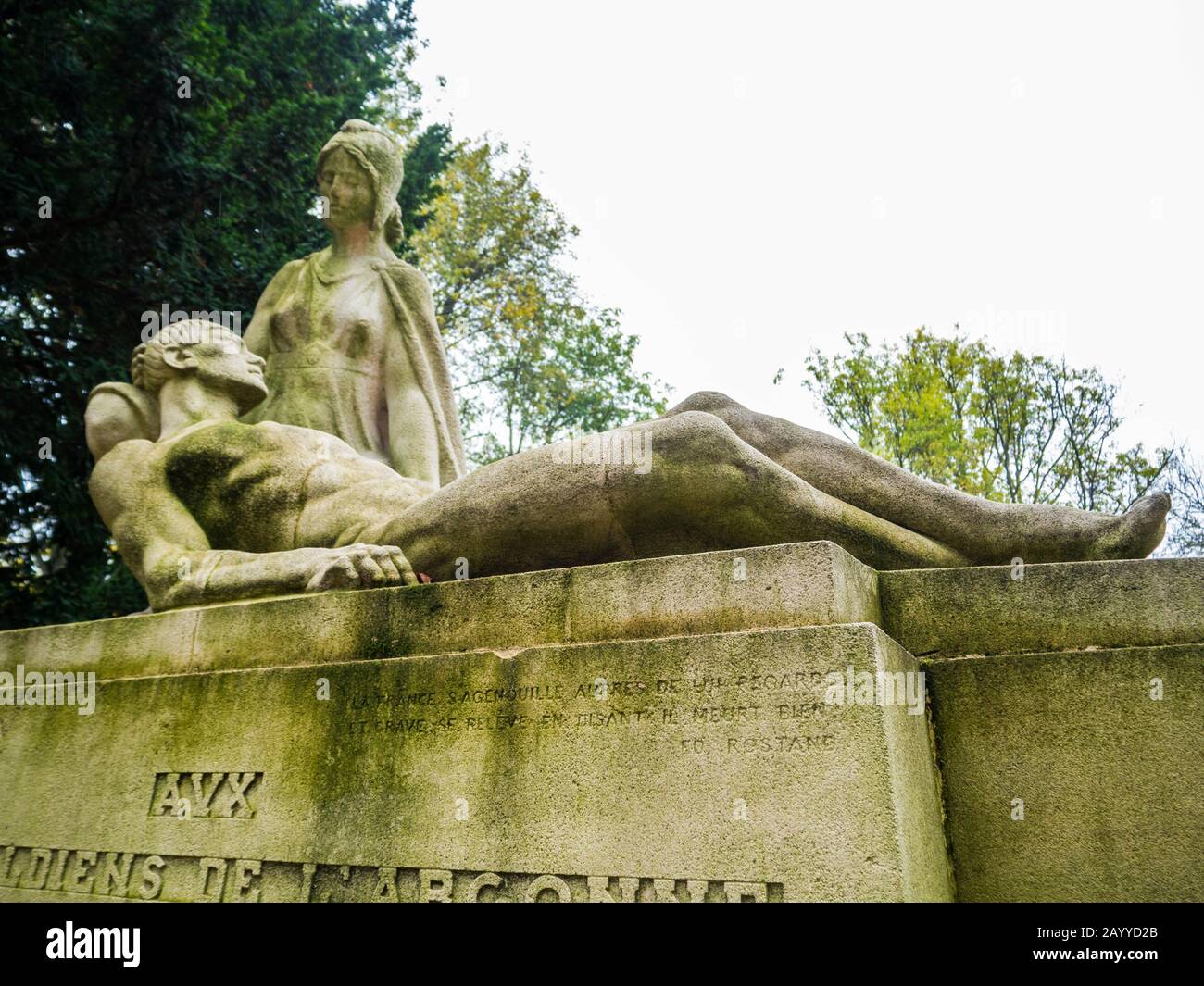 Trauerdenkmal aus weißem Stein mit den Statuen einer Frau trauernd ein starker Männer mit Bäumen im Hintergrund in einem monumentalen Friedhof Stockfoto