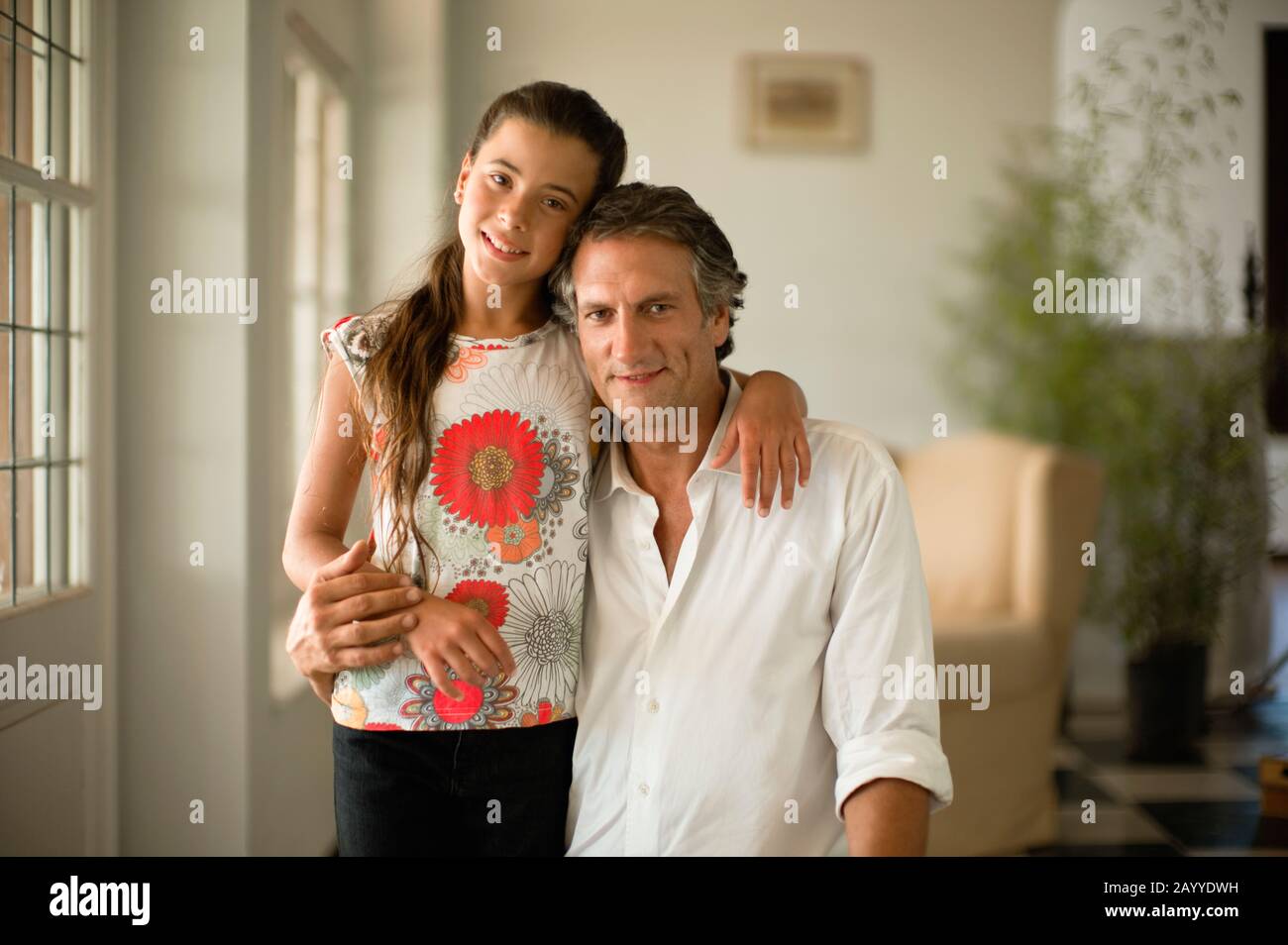 Im mittleren Alter Vater und sein vor - jugendlich Tochter lächeln für ein Porträt ihre Arme um die Schultern. Stockfoto