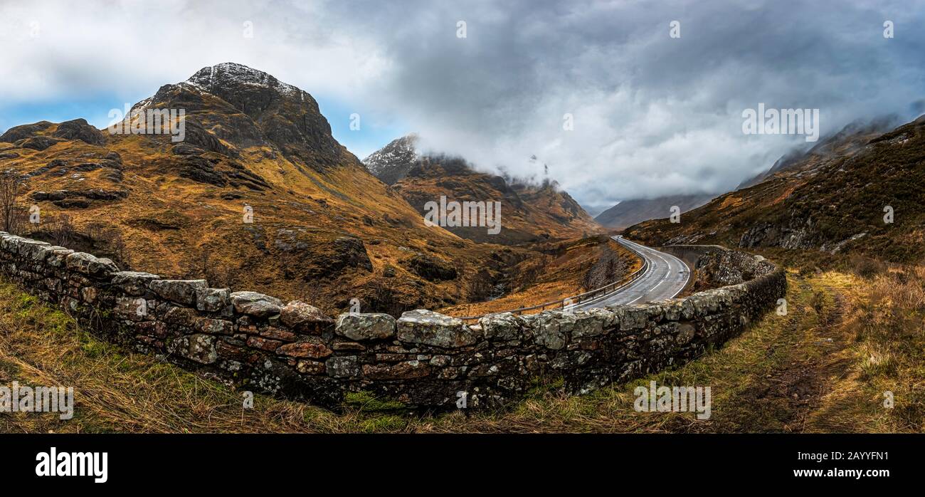 Glencoe, Schottland - Jan 2020: Panpramic Blick entlang einer Bergstraße auf die 3 Schwestern, da ein Wintersturm über die Decke zieht Stockfoto