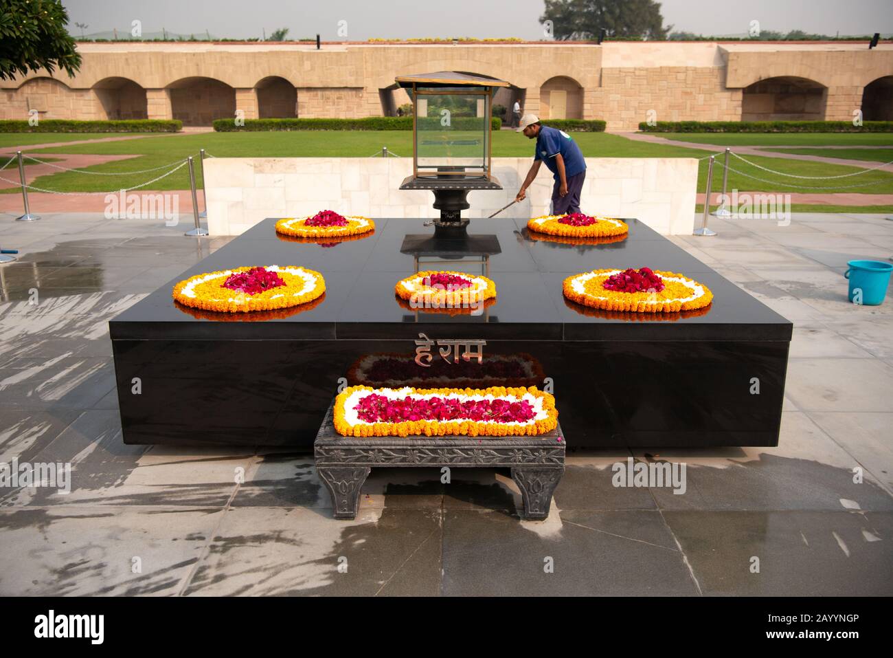 Ein Arbeiter reinigt um das merrigoldbeladene Mahnmal von Mahatma Ghandi in New Dehli, Indien. Stockfoto