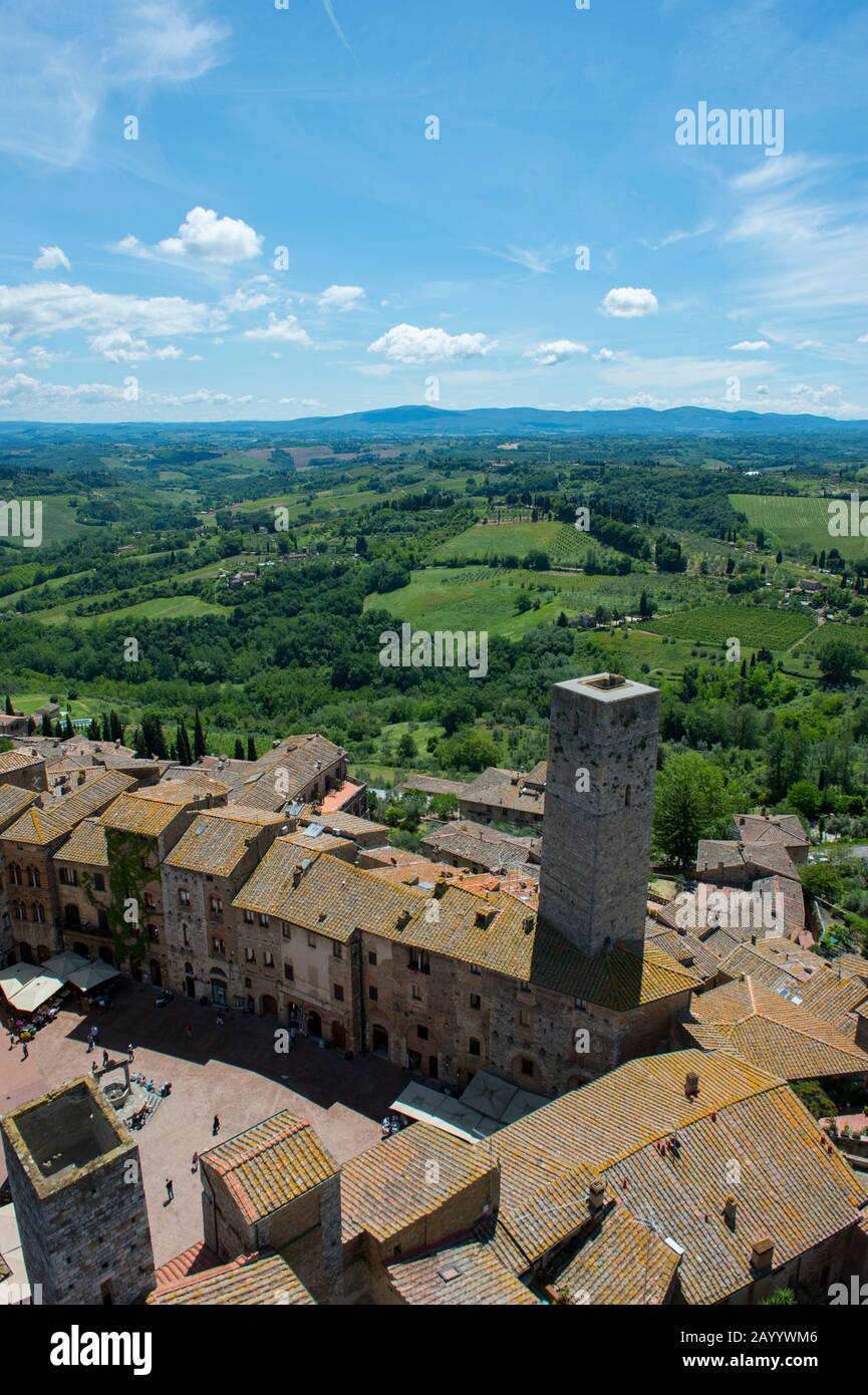 Blick von einem Turm der mittelalterlichen ummauerten Bergstadt San Gimignano in der Toskana, Italien und der umliegenden Landschaft. Stockfoto