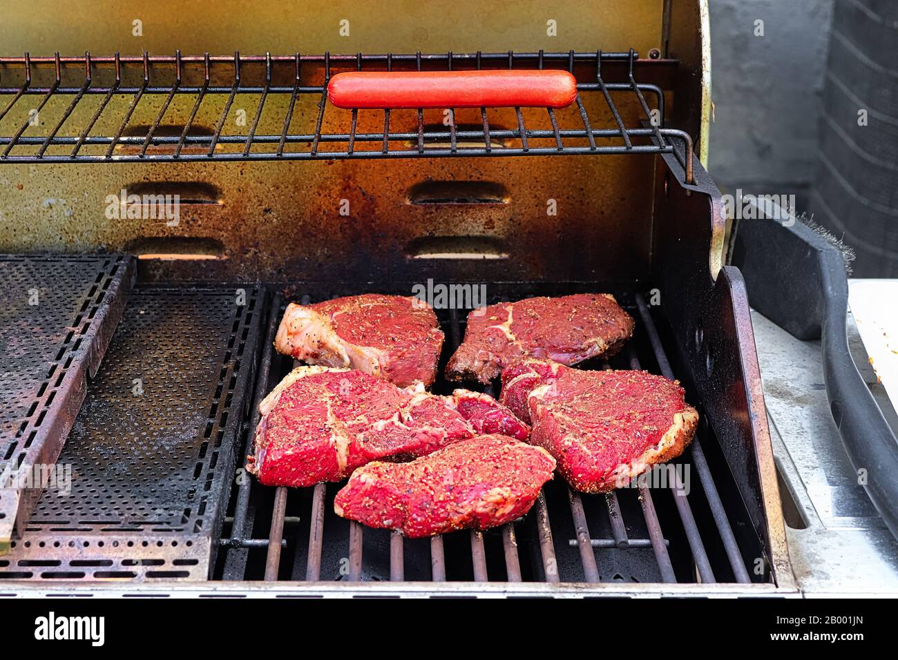 Rohe, gewürzte Steaks auf einem Grillgrill. Stockfoto